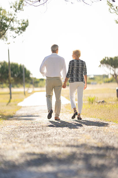 istock Senior couple walking away on a gravel path holding hands 2215516091