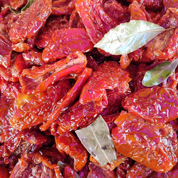 Bright red sun-dried tomatoes in olive oil and with bay leaf, appetizer, ingredient, background