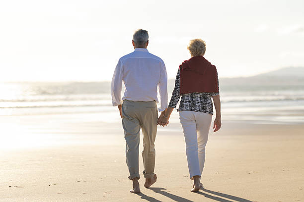 istock Senior couple walking on the beach at sunset holding hands 2215518872