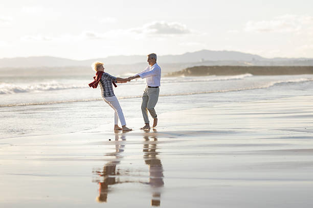 istock Happy senior couple holding hands and spinning on the beach 2215519668