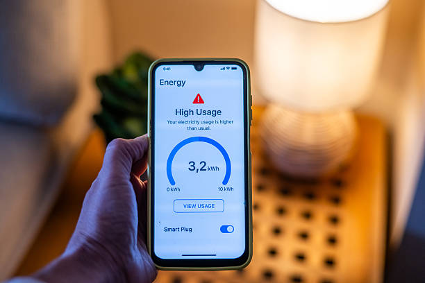 istock Hand holding smartphone displaying high energy usage alert from smart plug, indicating excessive electricity consumption compared to usual levels, prompting homeowner to take action 2215521927