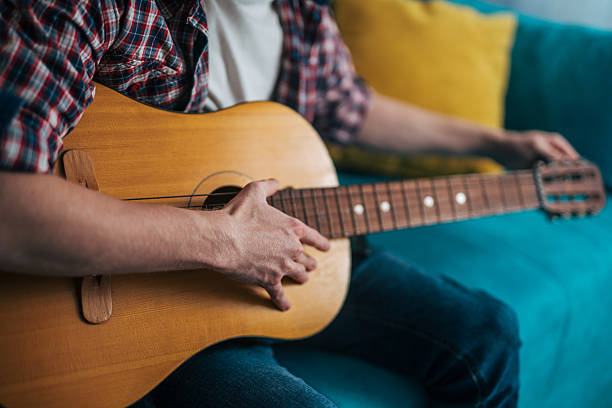 istock Musician playing acoustic guitar at home on turquoise sofa 2215522538