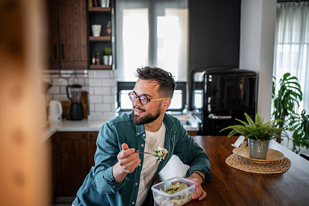 istock Young man eating healthy salad in modern kitchen 2215526852