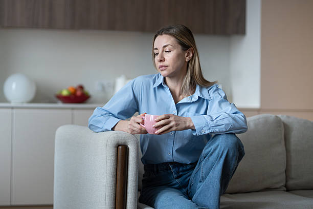 istock Melancholic lonely middle aged woman resting at home couch with coffee mug, deep in thought. 2215527549
