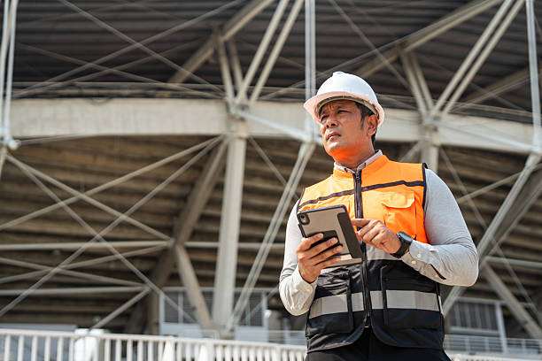 istock Asian senior engineer man or architect looking forward with white safety helmet in construction site. Standing at modern building construction. Professional asian man working project building 2215528228