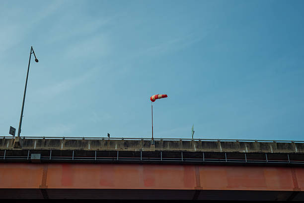 An orange and white wind direction measuring bag of a large bridge.