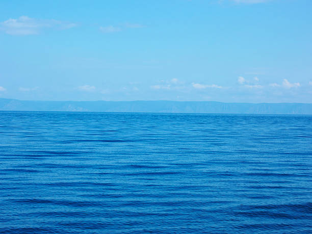 Clear blue ocean waves with distant horizon under bright sky.