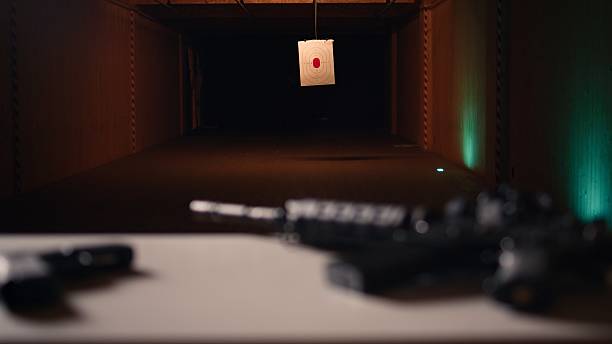 Practice weapons in military training outpost to be used by soldiers learning how to shoot firearms at paper target. Close up of pistol and rifle in army shooting range used for hitting bullseye