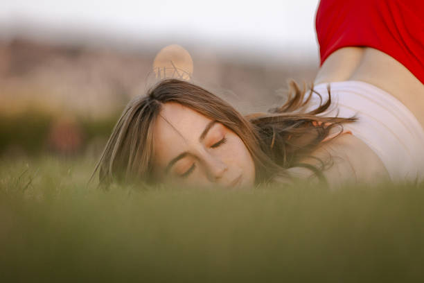 Portrait of beautiful girl wearing black leotard lying on grass and enjoying sunset in nature