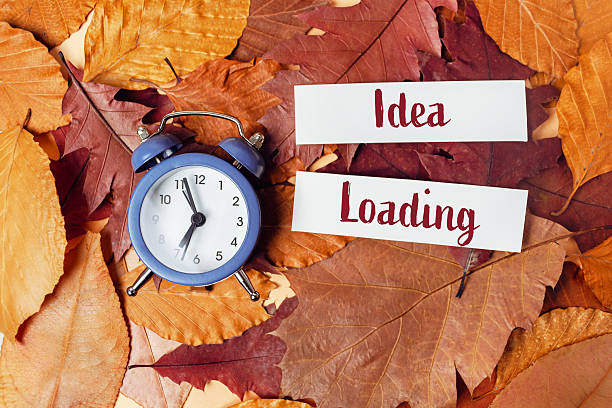 istock Clock is on a pile of leaves with the words idea loading written on a piece 2215546789
