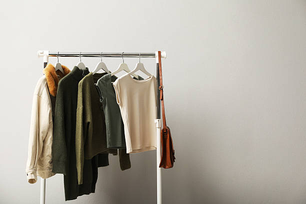 istock Rack with clothes and bag near light wall. Space for text 2215548471