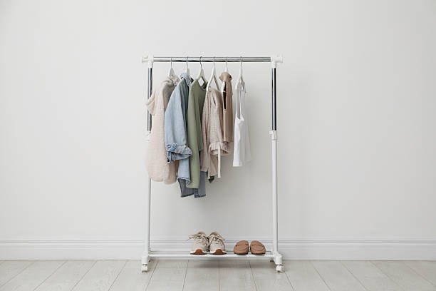 istock Rack with clothes and shoes near white wall 2215548477