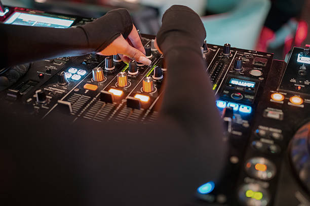 istock A DJ sets up a professional audio mixer surrounded by glowing buttons and displays, conveying the dynamics and technical aspect of live music mixing. 2215548485