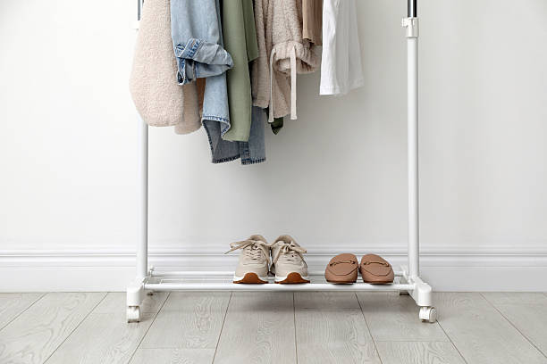 istock Rack with clothes and shoes near white wall 2215548499
