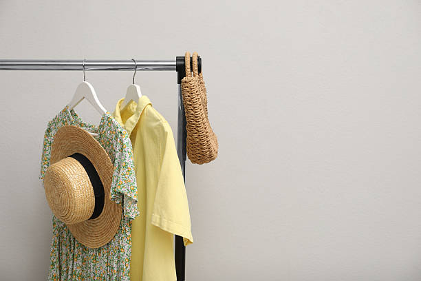 istock Rack with clothes and bag near light wall. Space for text 2215548528