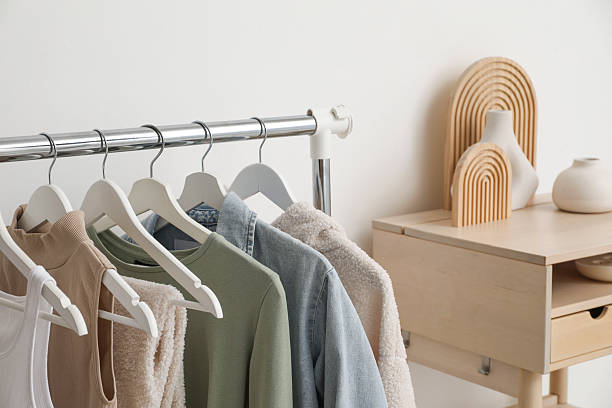 istock Rack with clothes and standing desk near white wall 2215548533