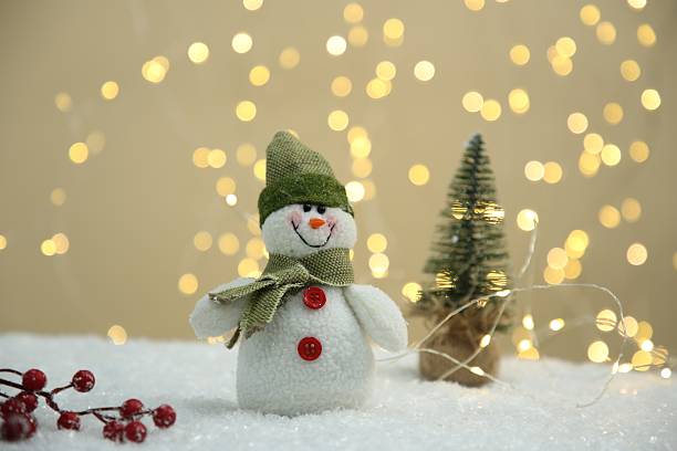 istock Cute decorative snowman and other Christmas decor on artificial snow against blurred lights 2215548572