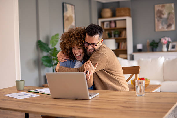 istock Young Diverse Couple Celebrating Good News While Working From Home On Laptop 2215548843