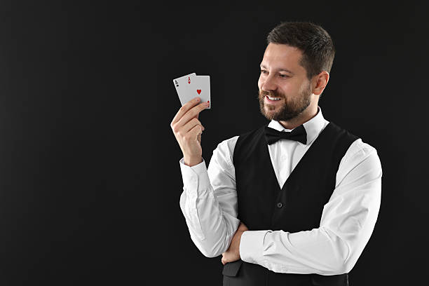 istock Professional croupier with playing cards on black background, space for text 2215549174