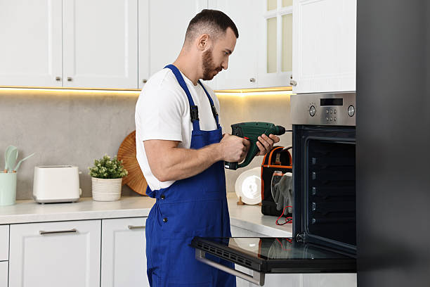 istock Repairman with drill fixing oven at home 2215549281