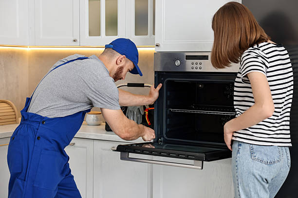 istock Woman looking how repairman fixing oven in kitchen 2215549939