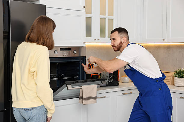 istock Woman looking how repairman fixing oven in kitchen 2215549972