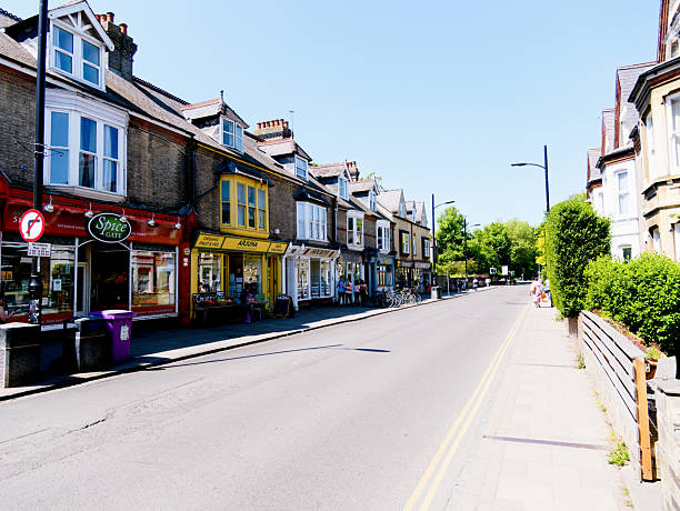 Cambridge, Cambridgeshire / United Kingdom - May 11th 2025: Line of multicultural businesses on Mill Road in Cambridge, pedestrians walking past