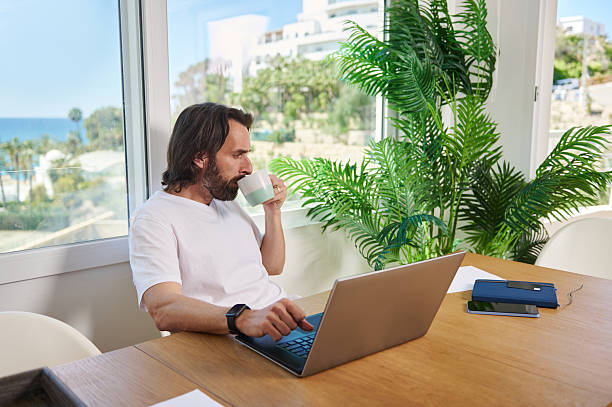 istock Remote Work Environment with Relaxed Man Working on Laptop in Minimalist Home Office Setting 2215555954