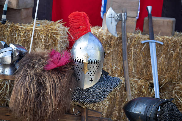 Medieval knight armor with helmet, sword, axe, and chainmail on display at historical reenactment event or fair. High quality photo