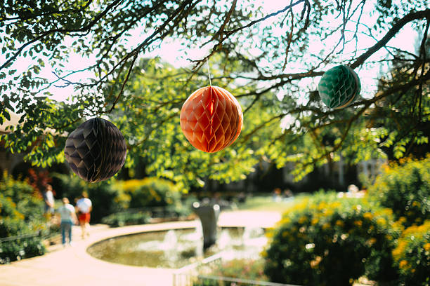 Three paper honeycomb ball decorations hanging in the tree in the park.
