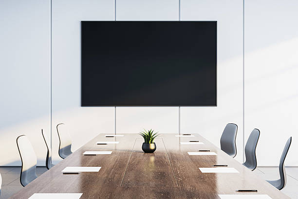 istock Modern empty conference room interior with large TV screen on wall, wooden desk, chairs and minimalist corporate design in bright lighting.. 3D Rendering 2215568498