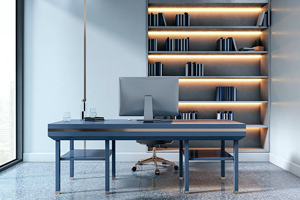istock Modern office desk with computer and illuminated bookshelf in clean corporate interior design concept with ambient light and city view background. 3D Rendering 2215568572