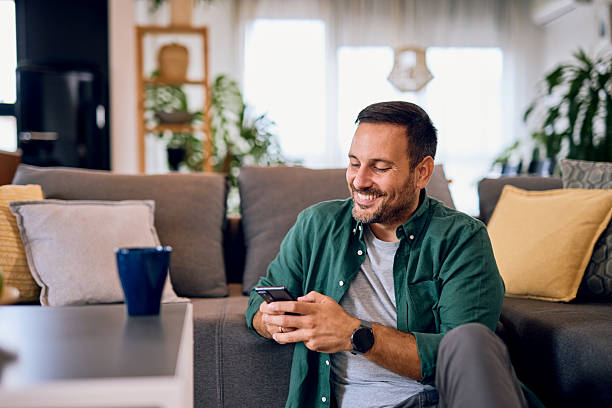 istock Man relaxing on floor using mobile phone at home 2215571432