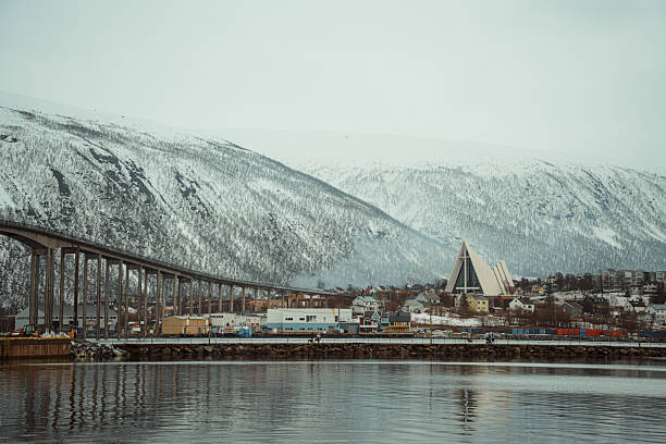 Scenic winter view of Tromso, Norway featuring the iconic Arctic Cathedral and snowy mountains.