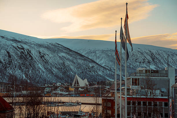 Scenic winter view of Tromso, Norway featuring the iconic Arctic Cathedral and snowy mountains.