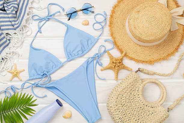 istock Blue bikini with beach accessories on wooden background, top view 2215577182
