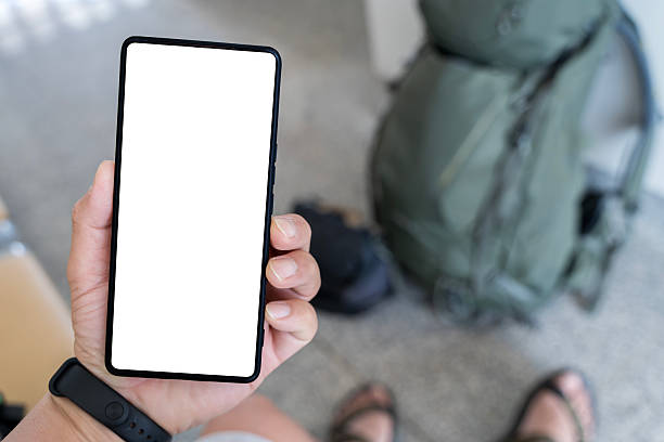 istock Traveler holding smartphone with blank screen while sitting at terminal with backpack. 2215578021