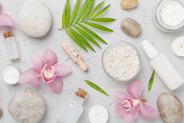 Composition with orchids and massage stones on concrete background, top view