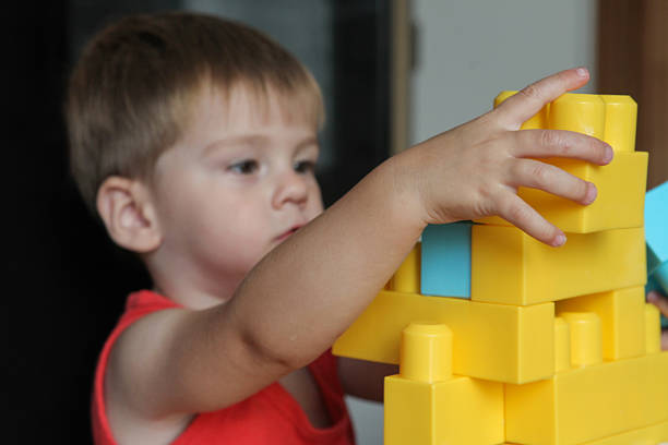 istock little  boy playing with plastic building blocks indoor 2215593215