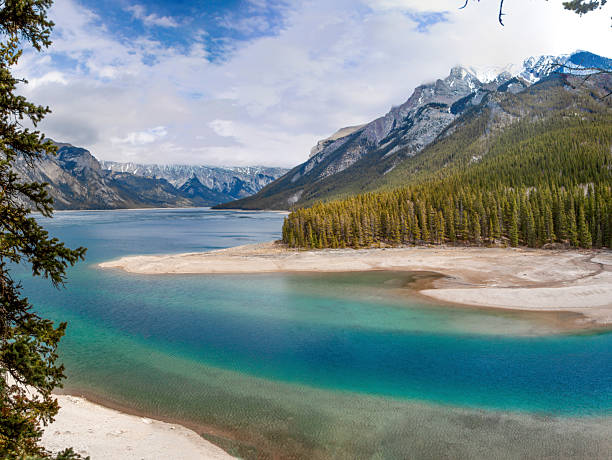 A breathtaking view of Lake Minnewanka in Banff National Park, Alberta, showcasing serene waters and majestic mountain landscapes.