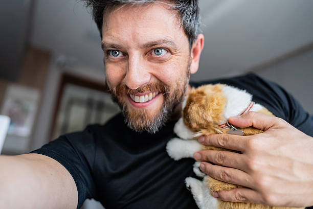 istock Smiling man enjoying a playful moment with his pet while using a mobile app 2215601371