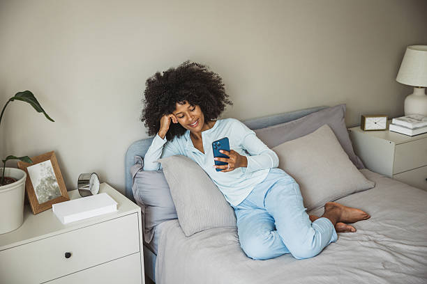 istock Young woman using smart phone during morning in bedroom 2215601646
