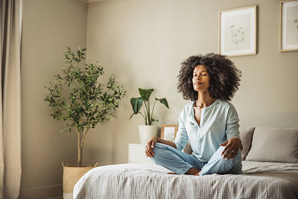 istock Relaxed black woman meditating during morning on a bed 2215602499