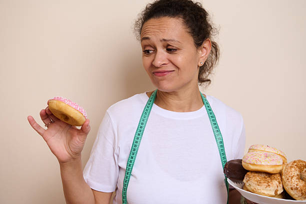 istock Woman Debating Between Indulgent Doughnuts and Healthy Choices, Representing Wellness 2215610593