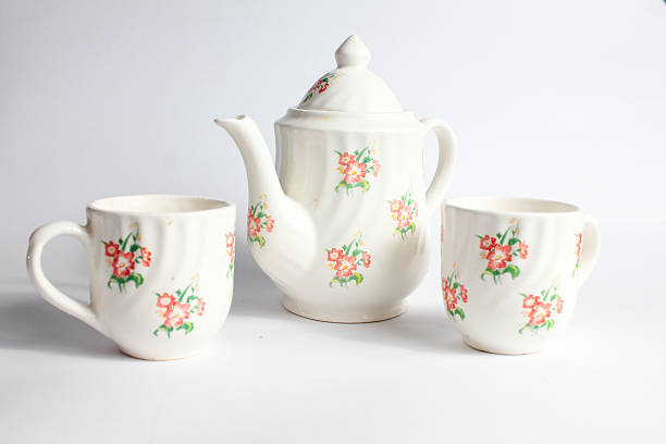 white ceramic teapot and cup with floral pattern isolated on white background