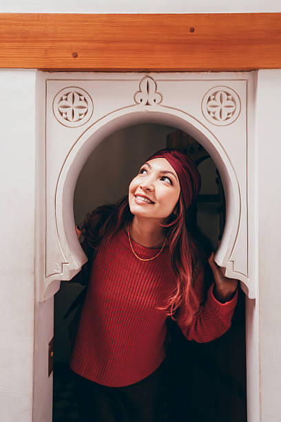 Young woman with a headscarf looking up and smiling while exploring traditional Moroccan architecture