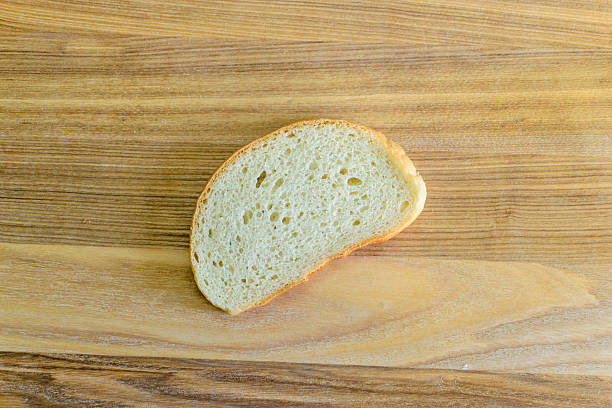 Simple slice of bread on wood. Ideal for food, diet, or culinary concepts. Minimalist style. Use for breakfast, lunch, recipes, or baking visuals.