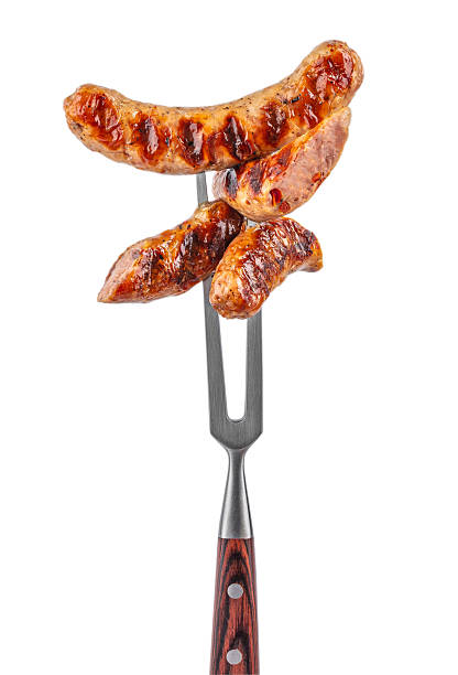 The grilled sausage on the fork isolated on white background.