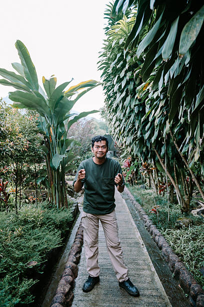 istock A Happy Man in Tropical Garden Inviting Someone with Hand Gesture 2215643522