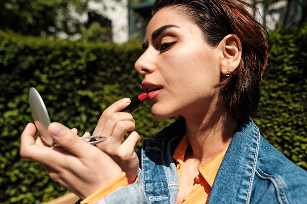 istock Woman applying red lipstick outdoors using pocket mirror 2215644736
